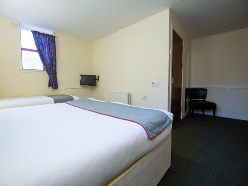 a hotel room with a bed and a window at Longforgan Coaching Inn in Dundee