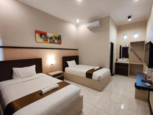a hotel room with two beds and a television at Hotel Orizatha in Mataram