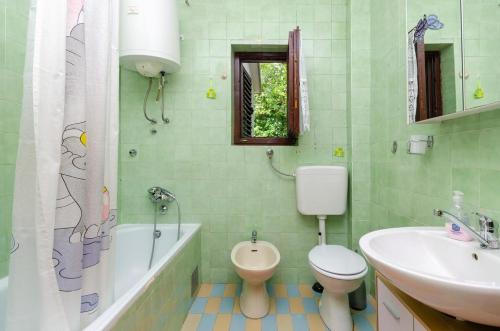 a bathroom with a toilet and a sink and a tub at OMERCIC in Jadranovo