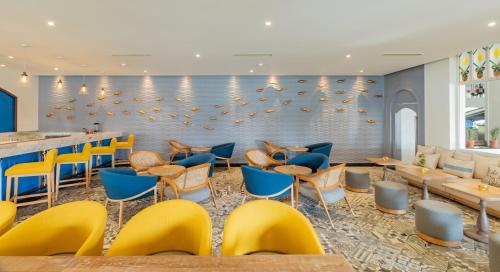 a restaurant with yellow and blue chairs and a bar at Heritage Village Resort & Spa Goa in Cansaulim