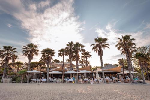 a resort with palm trees and tables on the beach at Marino Mobilhomes in Grimaud