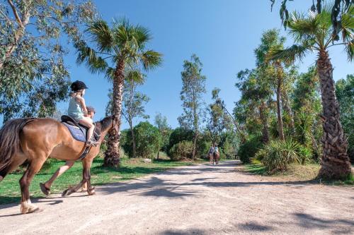 a woman and a child riding a horse on a dirt road at Marino Mobilhomes in Grimaud