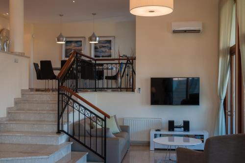 a living room with stairs with a couch and a tv at Villa HERMIONA in Kouklia