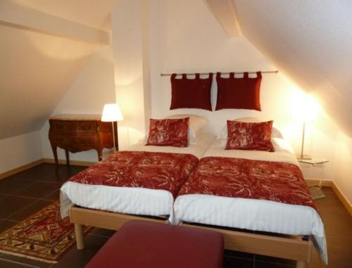 une chambre avec un grand lit avec des oreillers rouges dans l'établissement La Maison de Georges - Les Coquelicots, à Scharrachbergheim-Irmstett