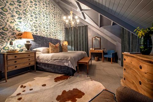 a bedroom with a bed and a dresser and a desk at Avondrood Guest House by The Oyster Collection in Franschhoek