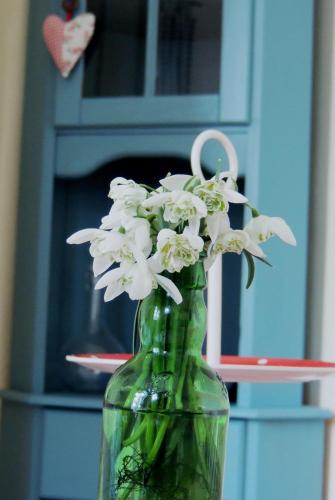 a green glass vase with white flowers in it at Pfarrhof Stuer in Stuer