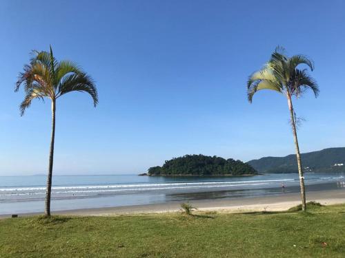 twee palmbomen op een strand met de oceaan bij Ubatuba Surf Hostel, apenas a 60 metros da praia da Lagoinha! in Ubatuba