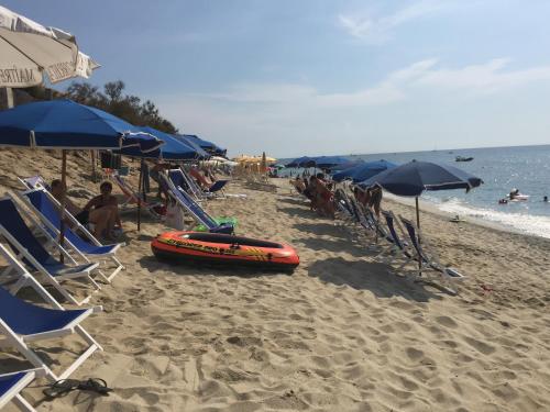 a sandy beach with chairs and umbrellas and a life preserver at Residenza Gherly in Capo Vaticano