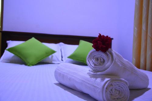 a bed with towels and a red flower on it at Seven Luck Palace in Kandy