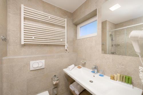 a bathroom with a sink and a mirror at Medora Auri Family Beach Resort in Podgora