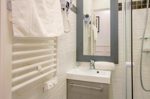 La salle de bains blanche est pourvue d'un lavabo et d'un miroir. dans l'établissement 25 - Fun Duplex in Montorgueil, à Paris