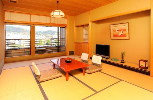 un soggiorno con tavolo, sedie e TV di Tazuru a Kyoto