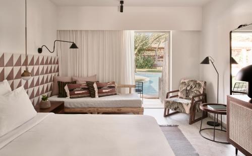 a bedroom with a bed and a couch and a chair at Phāea Cretan Malia, a Member of Design Hotels in Malia