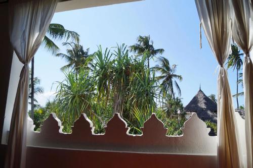 a window with a view of a palm tree at Laguna Palace Zanzibar in Michamvi