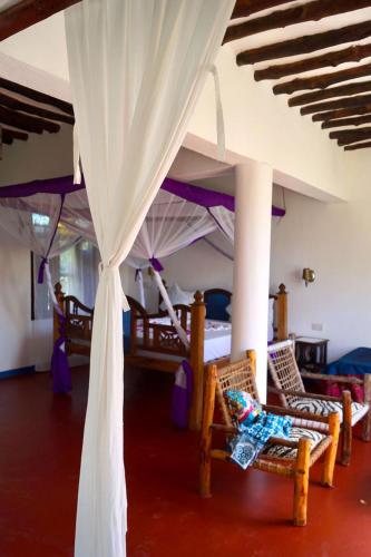 a room with two beds and a canopy at Laguna Palace Zanzibar in Michamvi