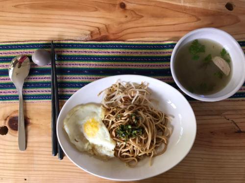 a plate of noodles with an egg and a bowl of soup at Tree House Café & Homestay in Tongluo
