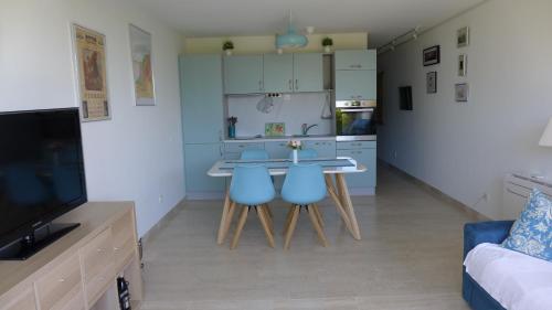une cuisine avec une table et deux chaises bleues dans l'établissement Les Trois Oliviers à Cassis, à Cassis