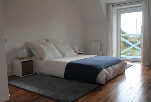une chambre blanche avec un lit et une grande fenêtre dans l'établissement Maison familiale-Surf House, plage de Sainte Barbe, à Plouharnel