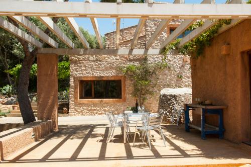 a patio with a table and chairs under a wooden pergola at Finca Pessal in Caʼs Concos
