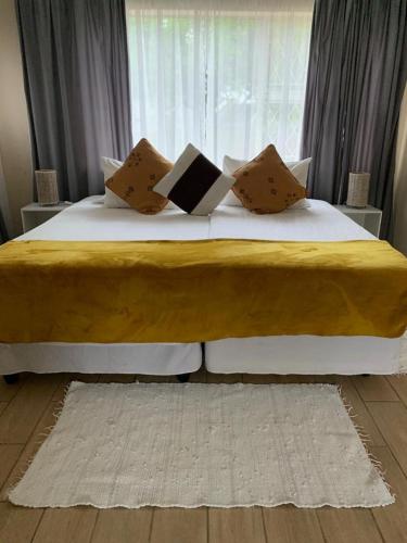 ein Schlafzimmer mit einem großen Bett mit Kissen und einem Fenster in der Unterkunft 77 on Sissons in Mthatha