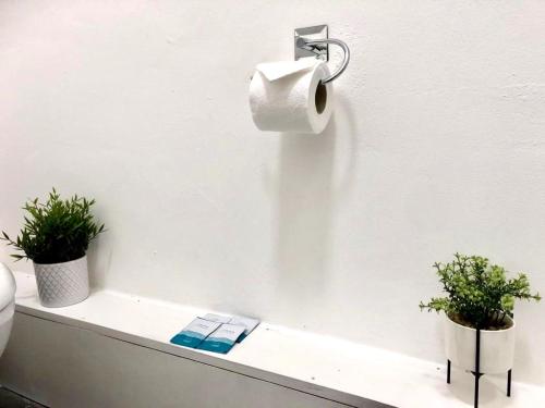 a bathroom with a toilet paper dispenser and two plants at BELMONT Apartments in Liverpool