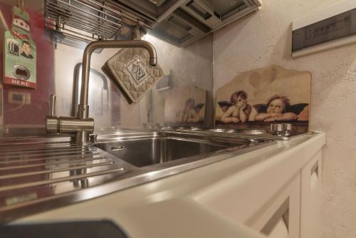uma cozinha com um lavatório de aço inoxidável com quadros na parede em Lovely Nest in Trastevere em Roma
