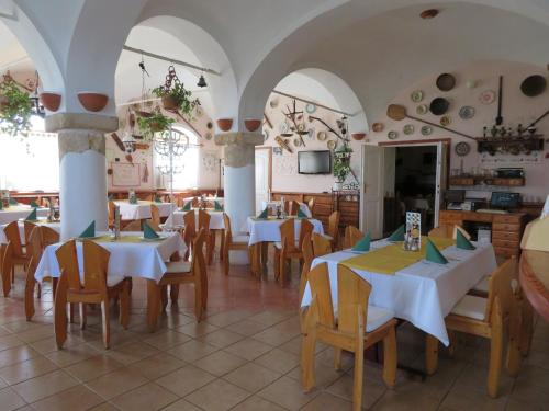 um restaurante com mesas brancas e cadeiras de madeira em Józsi Bácsi Szállodája em Szombathely