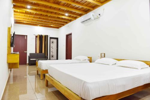 two beds in a room with white walls at Glucklich Beach Cottages in Kundapur