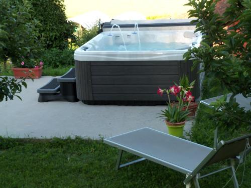 a hot tub in a yard with a bench and a table at Casa dei Ciliegi Castell'Alfero in CastellʼAlfero