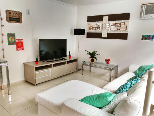 un salon avec un canapé blanc et une télévision dans l'établissement Suítes Paraty, à Parati