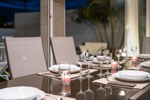 a table with glasses and plates and candles on it at Villa Dalara Maspalomas, Private Pool and Jacuzzi in Maspalomas