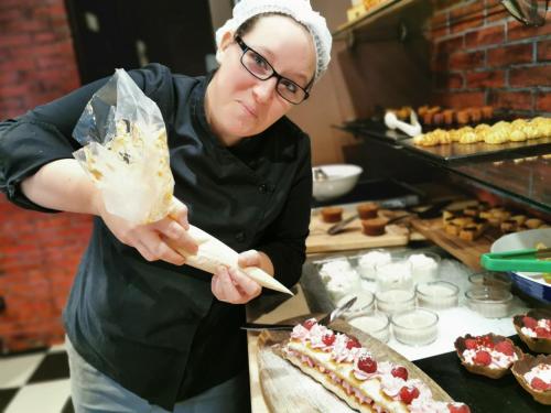 a woman in a kitchen holding a piece of food at Greenhotels Roissy Parc des Expositions in Tremblay En France