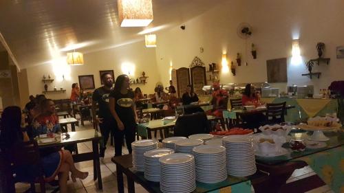 un grupo de personas de pie en una habitación con platos en las mesas en Molise Hotel Fazenda en Serra Negra