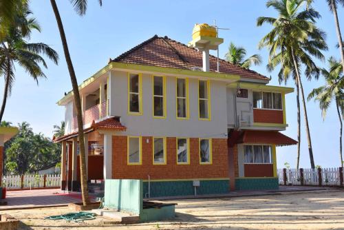 an old house with palm trees in the background at Glucklich Beach Cottages in Kundapur