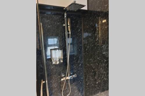 uma casa de banho com um chuveiro com paredes em granito preto em South Shield's Hidden Gem Garnet 3 Bedroom Apartment sleeps 6 Guests em South Shields