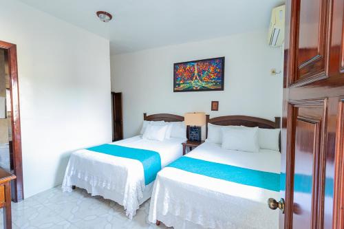 a bedroom with two beds and a painting on the wall at Hotel Casa Blanca by Rotamundos in Tlacotalpan