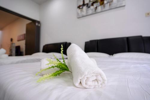a towel on a bed with a bouquet of flowers at Maison life 小居屋 The Loft Imago in Kota Kinabalu