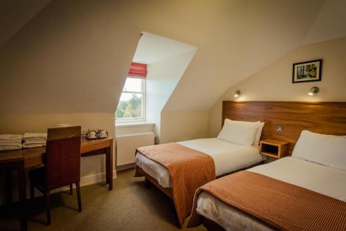 a bedroom with two beds and a desk and a window at DCU Rooms All Hallows in Dublin