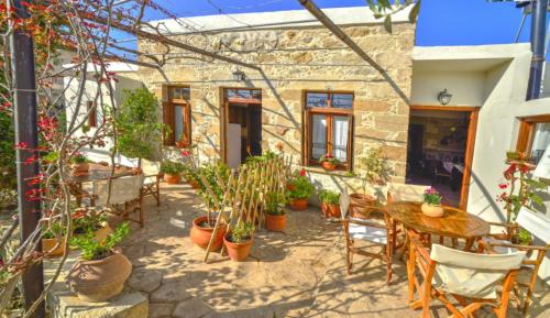 a patio with tables and chairs and potted plants at Picturesque Traditional Stone House in Plátanos