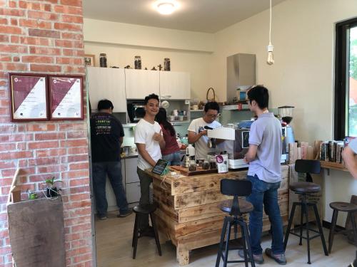 a group of people standing around a bar in a kitchen at Tree House Café & Homestay in Tongluo