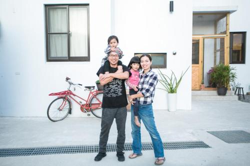 Eine Familie, die sich für ein Bild vor einem Haus ausgibt. in der Unterkunft Tree House Café & Homestay in Tongluo