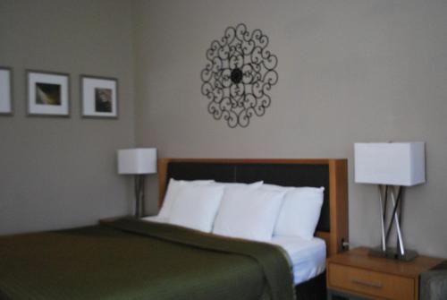 a bedroom with a bed with white pillows and two lamps at The Soluna Hotel in El Paso