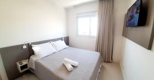 1 dormitorio pequeño con 1 cama con 2 toallas en Apartamento Gaivotas - 20 metros do mar, lazer e home office, en Florianópolis