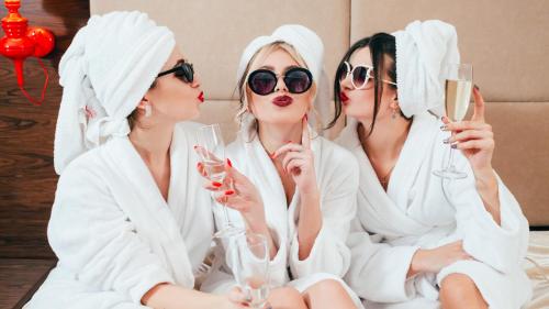 three women in white robes drinking wine in a room at Creative Design House Golf & SPA in Pozzolengo