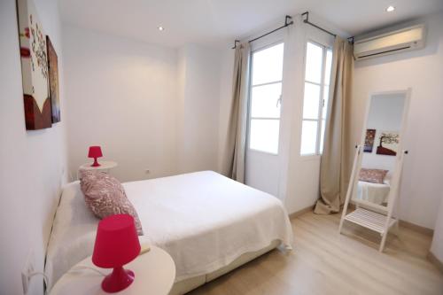 Apartamento Mediterraneo في مالقة: غرفة نوم بيضاء بها سرير ونافذة