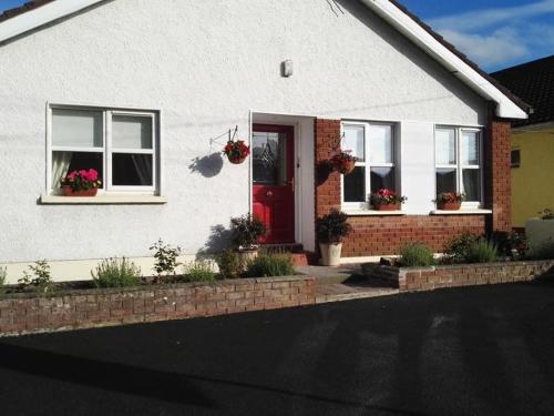 Casa blanca con puerta roja y 2 ventanas en The Vee Guest Accommodation, en Waterford