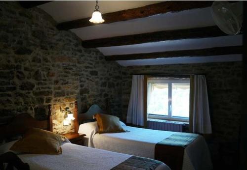 a bedroom with two beds and a brick wall at Casa Rural La Choca in Lecina