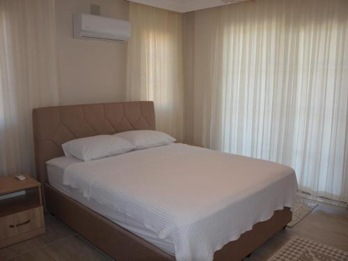 - une chambre avec un lit doté de draps blancs et une fenêtre dans l'établissement Konak Sari, à Dalyan