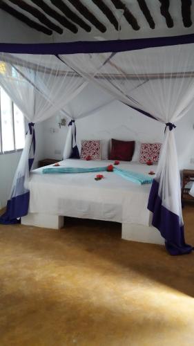 a bedroom with a white bed with a canopy at Laguna Palace Zanzibar in Michamvi