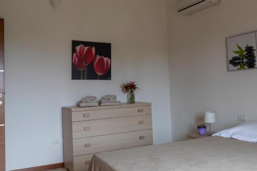a bedroom with a bed and a dresser with red flowers at Case Fiorite in Riola Sardo